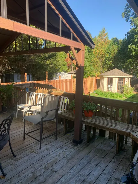 Wooden deck and chairs overlooking a fenced garden and gazebo