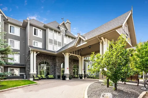 Residence with a stone facade, peaked entrance canopy and seating outside