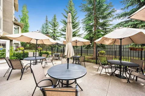 Patio with round tables, chairs, umbrellas and hanging flower baskets