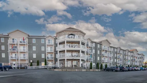 Grey residence with white balconies, a stone entrance and parking spaces