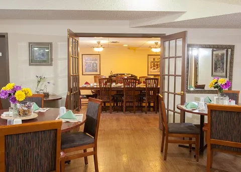 Dining room with set tables beyond open double doors.
