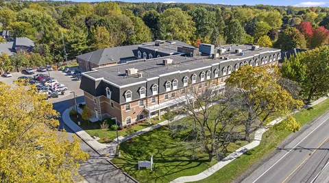 Aerial view of the residence building, grounds and surrounding street.