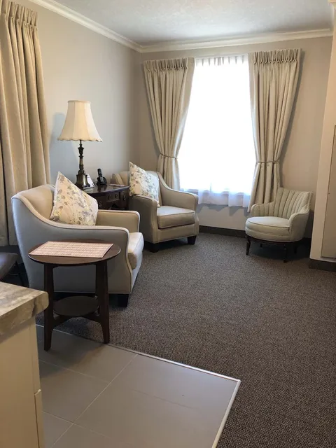 Suite sitting room with armchairs beside a window.