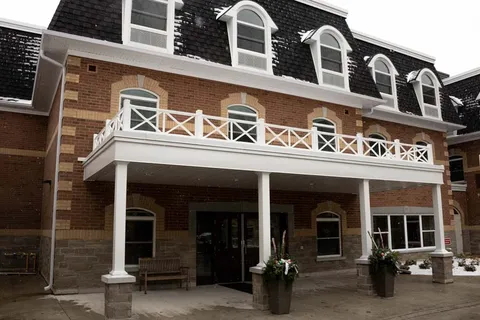Covered entrance beneath a balcony and dormer windows.