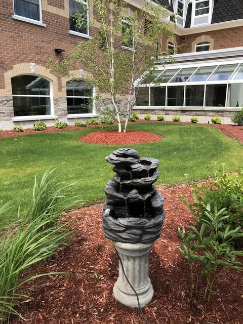 Garden fountain beside landscaped beds and the residence.