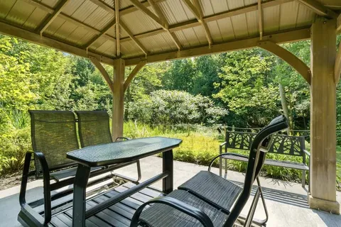 Covered gazebo with a table and chairs beside trees