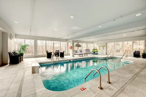 Indoor swimming pool with large windows and nearby seating