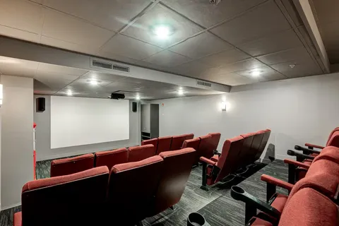Theatre with red seats facing a blank projection screen