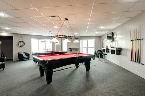 Room with two pool tables, armchairs and a cue rack