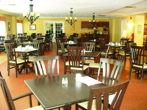 Dining room with wooden tables, chairs and pendant lights.