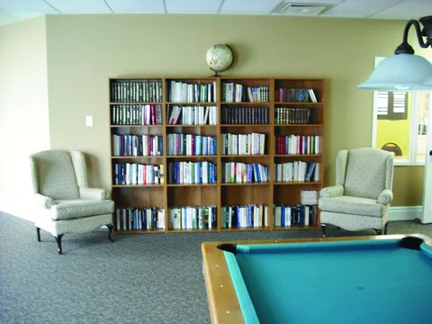 Bookshelf and armchairs beside a billiard table.