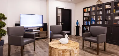 Armchairs and a round table beside bookcases and a television
