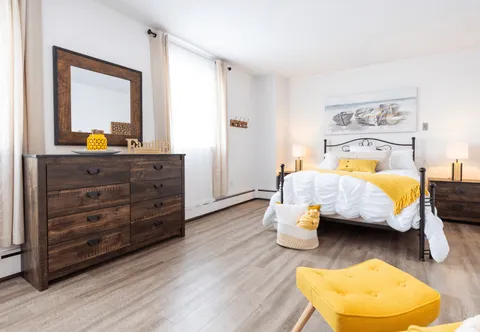 Bedroom with a metal-framed bed, dresser and yellow accents