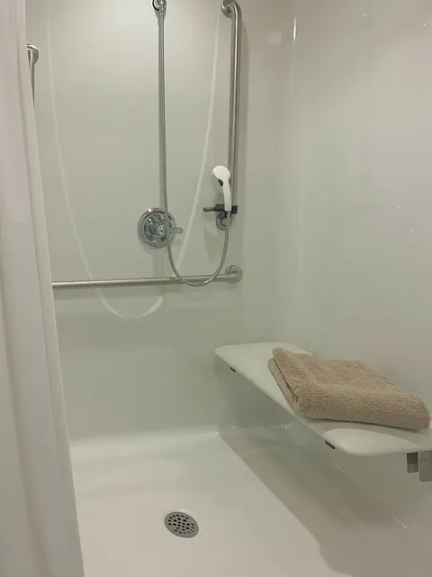 Walk-in shower with a handheld showerhead, grab bars and a folding seat