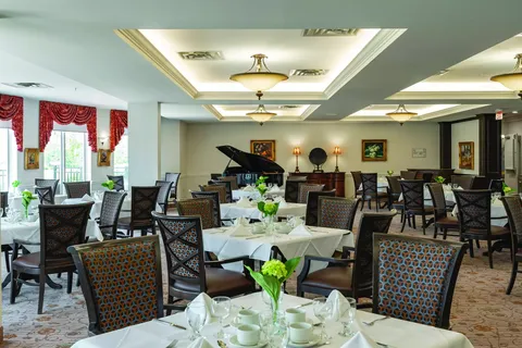 Dining room with set tables, upholstered chairs and a grand piano