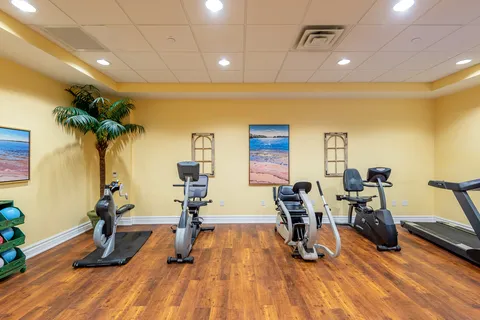 Exercise room with stationary bicycles, a treadmill and framed beach pictures
