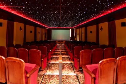 Rows of red theatre chairs facing a blank screen beneath a star-patterned ceiling
