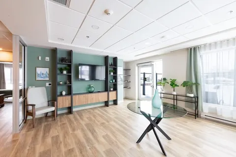 Common room with a television, chairs and a round glass table.