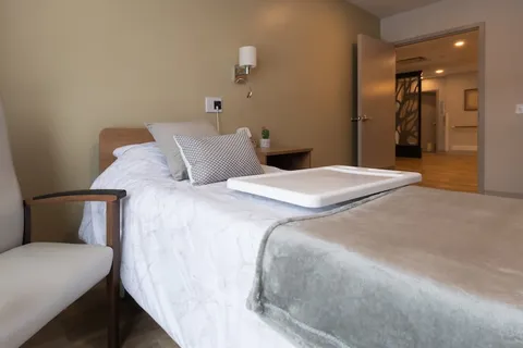 Bedroom with a bed, chair and an open doorway.