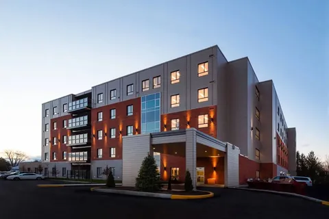 Residence exterior at dusk with balconies and a covered entrance.