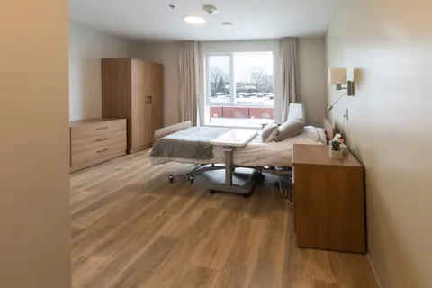 Bedroom with a bed, bedside drawers and a large window.