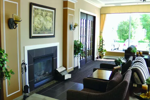 Lounge with sofas and a fireplace beside large windows.