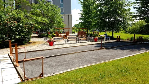 Outdoor recreation court beside planted grounds and patio seating.