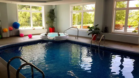 Indoor swimming pool and spa beside large windows.