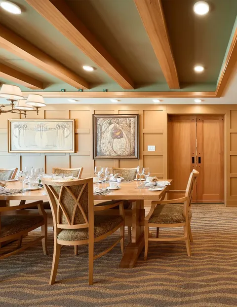 Private dining room with a wood table, upholstered chairs and framed maps.