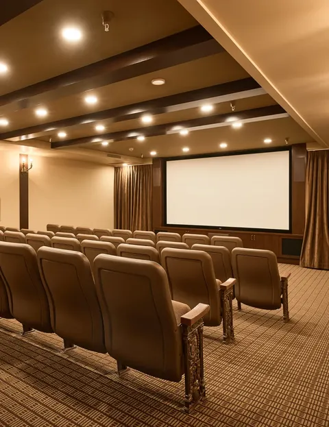 Theatre with rows of upholstered seats and a blank projection screen.