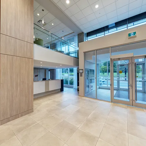 Glass entrance doors in a bright foyer with tile flooring and tall windows