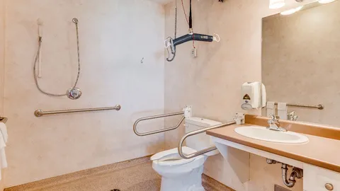 Accessible bathroom with a shower, sink, toilet and grab rails.