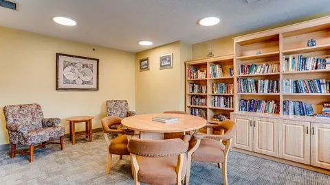 Library corner with bookshelves, chairs and a round table.