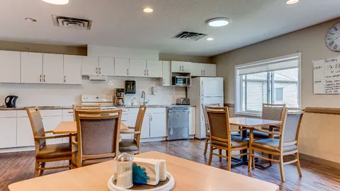 Dining area with tables and chairs beside shared kitchen cabinets.