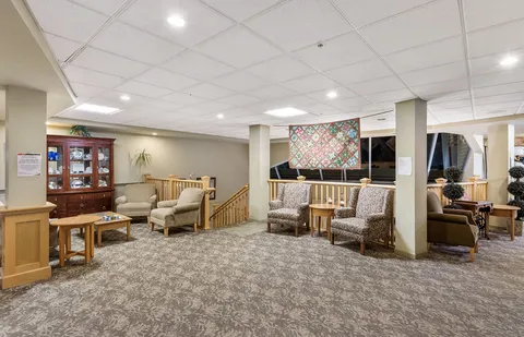 Sitting area with armchairs, a display cabinet and a colourful quilt