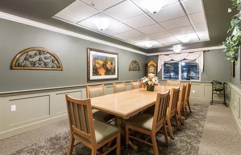 Long wooden dining table and chairs beneath framed landscape art