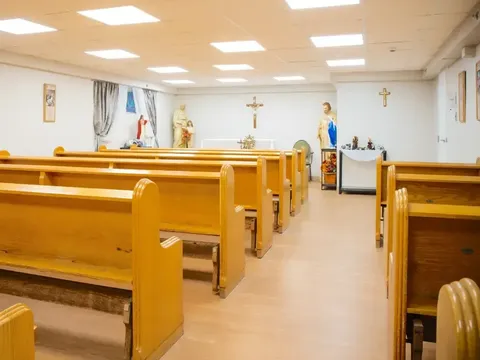Chapel with wooden pews and religious statues.