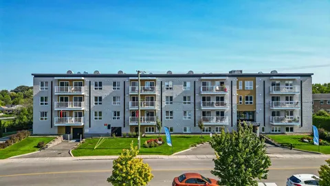 Front of the residence with balconies and landscaped grounds.
