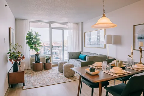 Apartment living room and dining table beside large windows.