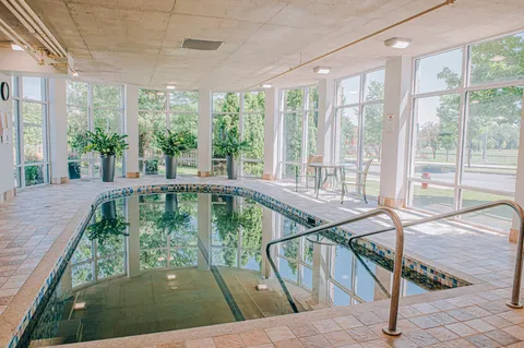 Indoor swimming pool beside large windows.
