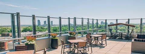 Rooftop terrace with patio tables and a glass railing.