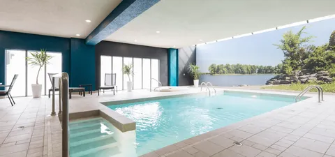Indoor pool beside large windows and a landscape wall mural