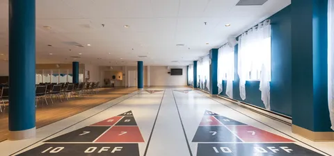 Indoor shuffleboard courts beside rows of chairs