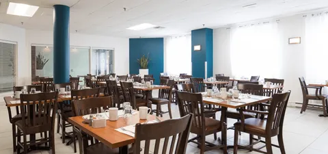 Dining room with wooden tables, dark chairs and blue columns
