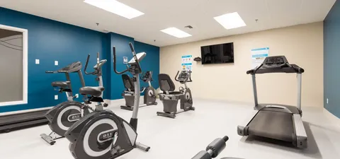 Exercise room with stationary bicycles, a treadmill and dumbbells