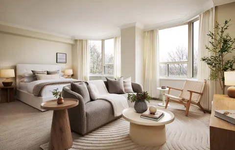Studio suite with a bed, sofa, armchair and large windows.