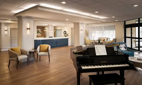 Reception lounge with a grand piano, seating and a reception counter.