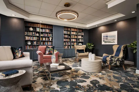 Library with bookcases, upholstered chairs and sofas.