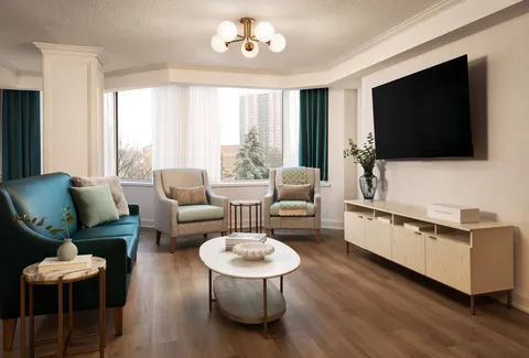 Lounge with upholstered seating, a television and large windows.