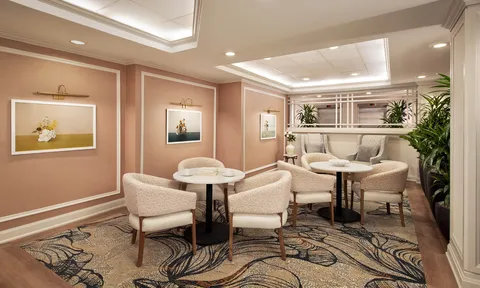 Sitting area with upholstered chairs, round tables and framed artwork.